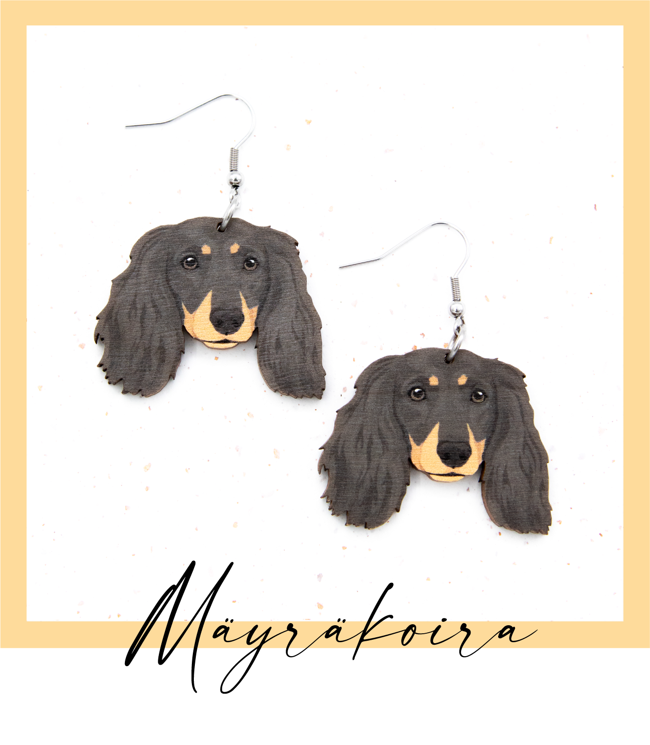 Suomalaisesta koivuvanerista ja kirurginteräksestä valmistetut roikkuvat musta punaisin merkein pitkäkarvainen mäyräkoira korvakorut